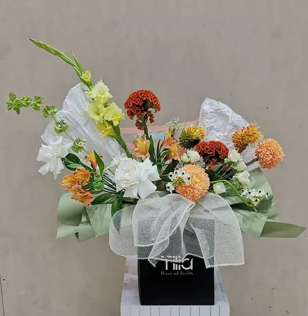 Orange and cream flowers with white tulle in a black Tilia box
