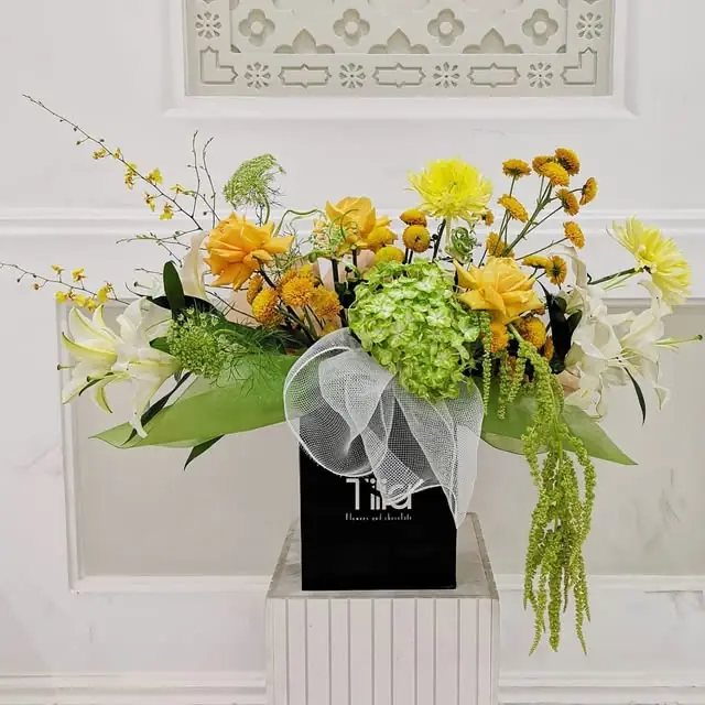 Yellow and green flowers with white tulle in a black Tilia box